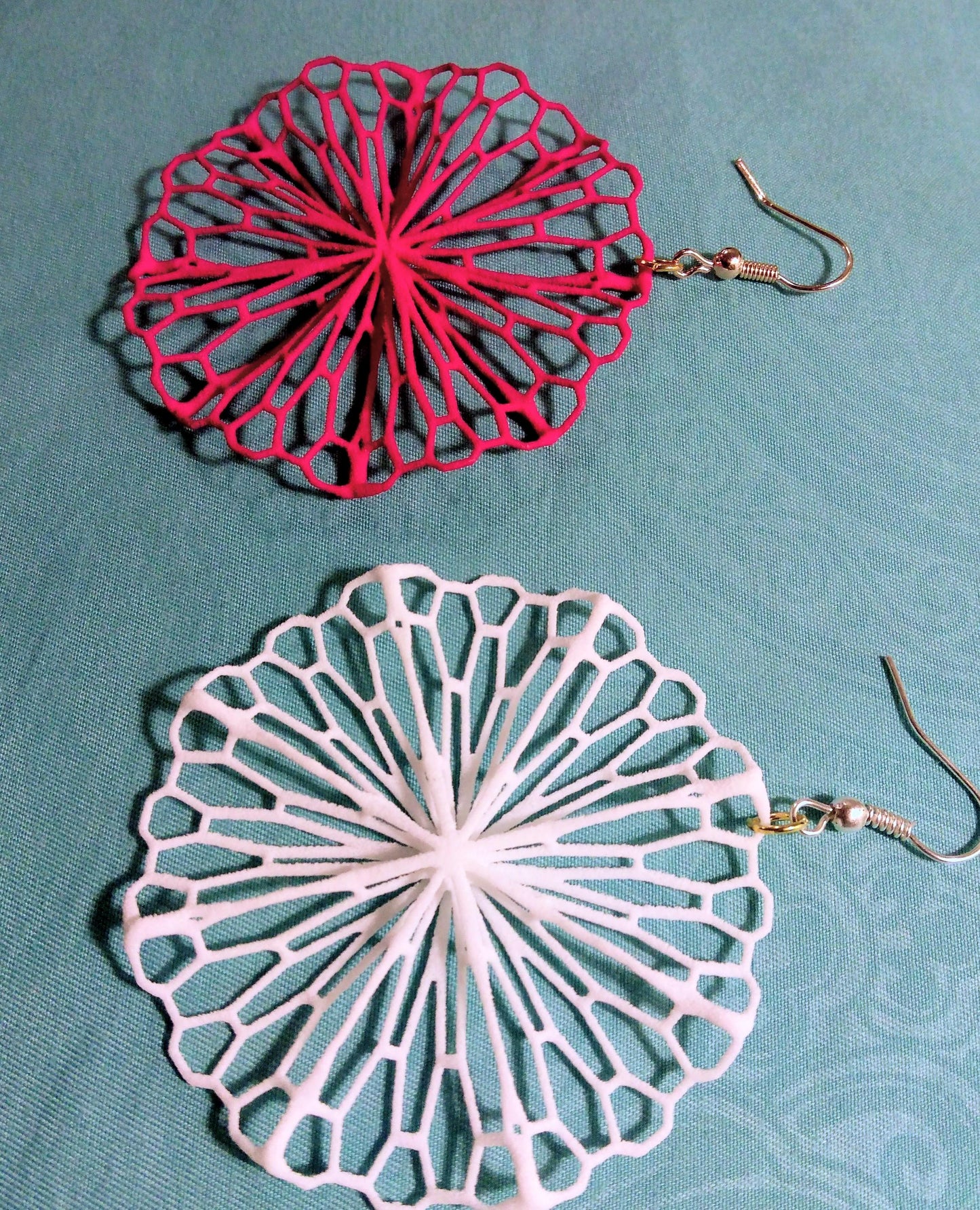a pair of pink and white earrings on a blue surface