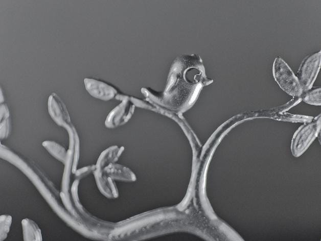 a metal sculpture of a bird on a tree branch
