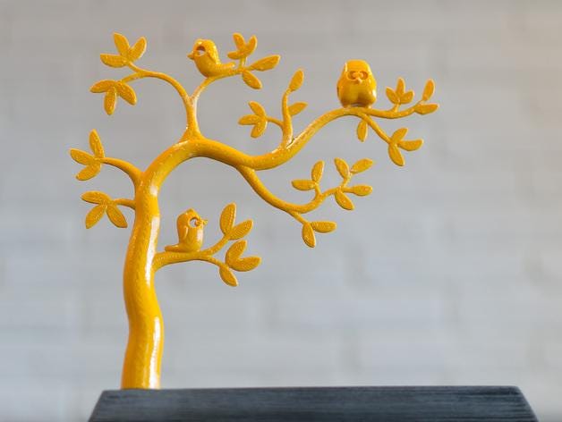 a yellow figurine of a tree with birds on it