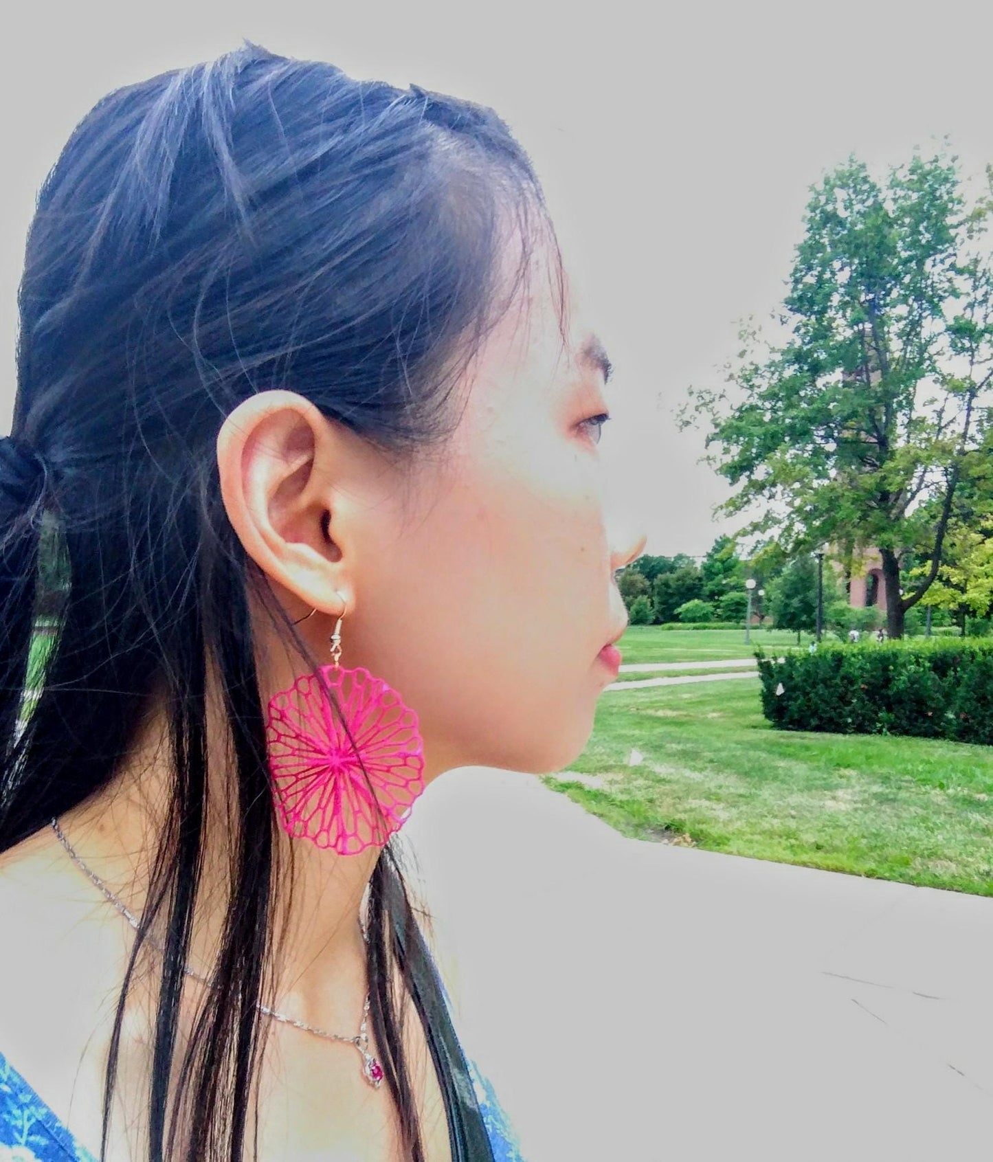 a woman with long black hair wearing pink earrings