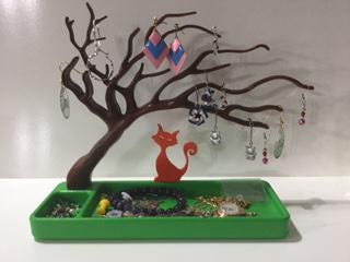 a green tray with a tree and earrings on it