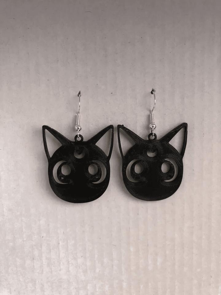 a pair of black cat earrings hanging from a hook