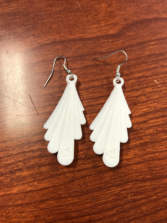 a pair of white earrings sitting on top of a wooden table