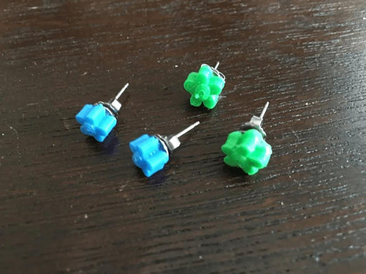 four small green and blue studs on a wooden table