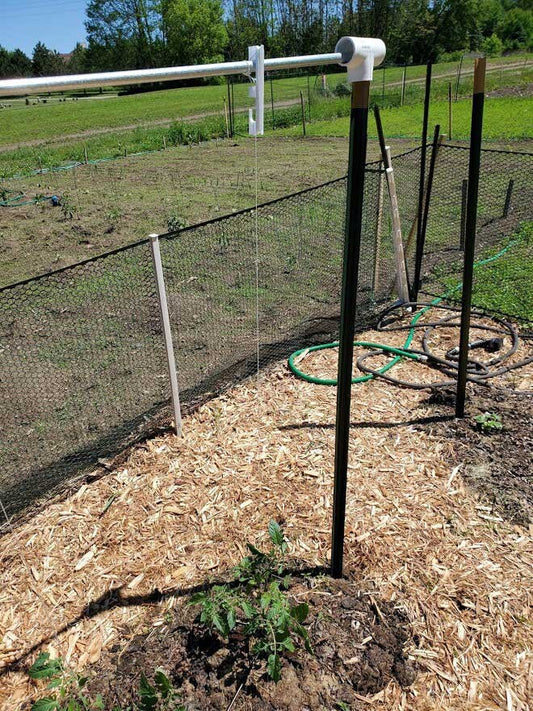 a fenced in garden with a hose attached to it