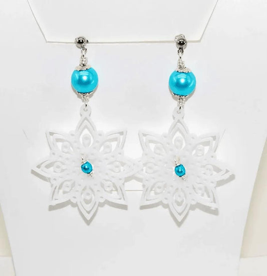 a pair of white and blue earrings on a white mannequin