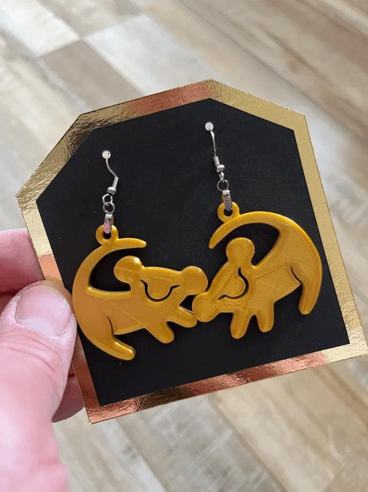 a hand holding a pair of yellow earrings