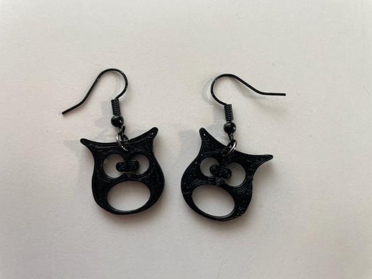 a pair of black earrings with an owl design