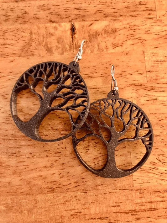 a pair of tree of life earrings on a wooden table